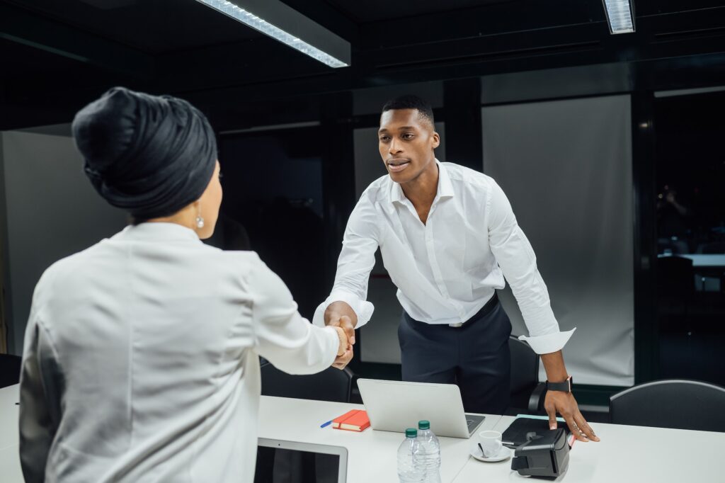 Businessman and woman shaking hands over conference table